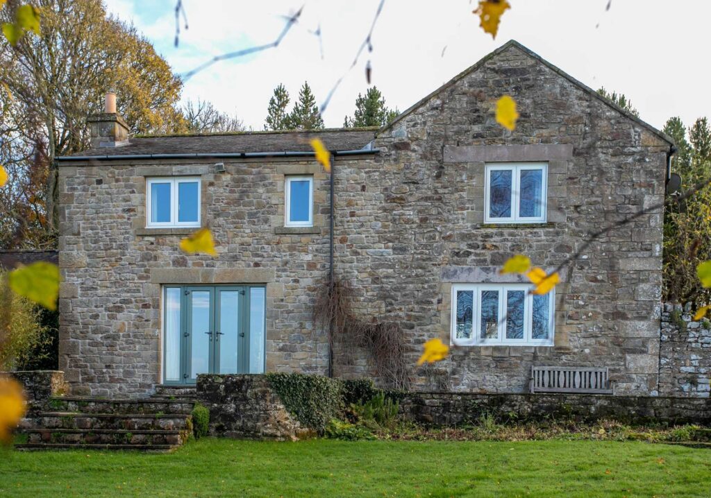 Rear elevation of a Northumberland stone home with energy-efficient double glazed windows and patio doors